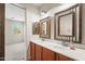 Stylish bathroom with double sinks, decorative mirrors, and a view into the attached bedroom at 14916 W Georgia Dr, Surprise, AZ 85379