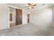 Large main bedroom with neutral carpet, ceiling fan, and a rustic barn door leading to the bathroom at 14916 W Georgia Dr, Surprise, AZ 85379