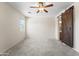 Spacious primary bedroom boasts neutral carpet, ceiling fan, and barn door to the luxurious bathroom at 14916 W Georgia Dr, Surprise, AZ 85379