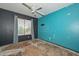 Bedroom featuring turquoise and black walls with damaged floors and ceiling fan at 16112 W Durango St, Goodyear, AZ 85338