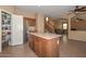 Kitchen with stainless steel refrigerator, island with cabinets, and adjoining staircase and living room at 16112 W Durango St, Goodyear, AZ 85338