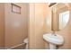 Powder room featuring a pedestal sink, round mirror, and neutral walls at 16112 W Durango St, Goodyear, AZ 85338
