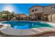 A spacious backyard with a custom-shaped pool and desert landscaping with mature trees at 16153 W Lisbon Ln, Surprise, AZ 85379