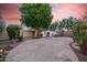 Relaxing backyard with desert landscaping, a fireplace, and seating area under the trees at 16153 W Lisbon Ln, Surprise, AZ 85379