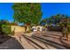 Spacious backyard with fireplace, patio seating under a mature tree, and lush landscaping at 16153 W Lisbon Ln, Surprise, AZ 85379