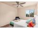 Bright bedroom featuring a ceiling fan, window view, and decorative pillows and throw at 16153 W Lisbon Ln, Surprise, AZ 85379