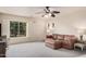 Large living room featuring a brown sectional sofa, carpet flooring, and window with plantation shutters at 16153 W Lisbon Ln, Surprise, AZ 85379