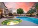 Inviting backyard pool and spa featuring mature landscaping, lounge chairs, and a tranquil sunset sky at 16153 W Lisbon Ln, Surprise, AZ 85379