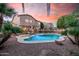 Backyard pool with hot tub, safety fence, desert landscaping, and home exterior in the background at 16153 W Lisbon Ln, Surprise, AZ 85379