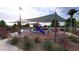 A playground with various play structures, sun shades, and landscaping for outdoor recreation at 16932 W Desert Hollow Dr, Surprise, AZ 85387