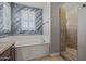 An elegant bathroom with modern tub, decorative wood wall, and tiled walk-in shower offers a luxurious feel at 21104 W Sage Hill Rd, Buckeye, AZ 85396