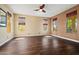 Spacious bedroom with hardwood floors, neutral paint, ceiling fan, and an array of sunlit windows at 21104 W Sage Hill Rd, Buckeye, AZ 85396