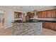 Open concept kitchen with a stone breakfast bar, stainless steel appliances, and rich wood cabinetry at 21104 W Sage Hill Rd, Buckeye, AZ 85396