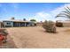 Spacious backyard with a charming blue house featuring white-trimmed windows, desert landscaping, and block fence at 2144 W 1St Pl, Mesa, AZ 85201
