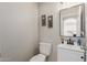 Powder room with white vanity, toilet, decorative mirror, and light fixtures at 21972 W Pima St, Buckeye, AZ 85326