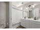 Bathroom featuring a white vanity with double sinks, a large mirror, and a shower with a white shower curtain at 21972 W Pima St, Buckeye, AZ 85326