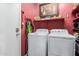 Functional laundry room with a washer, dryer, and ample storage space on red shelving at 28834 N Spur Dr, San Tan Valley, AZ 85143