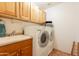 Well-equipped laundry room with modern washer and dryer, sink, and wooden cabinets at 39017 N Habitat Cir, Cave Creek, AZ 85331
