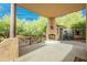 Inviting covered patio with a rustic fireplace, iron railings, and lush desert landscaping at 39017 N Habitat Cir, Cave Creek, AZ 85331