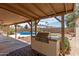 Outdoor kitchen with a built-in grill beside a sparkling pool and covered patio in a private backyard at 4803 W Harmont Dr, Glendale, AZ 85302