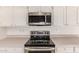 Close up of modern kitchen appliances, including a stainless steel microwave and range at 4803 W Harmont Dr, Glendale, AZ 85302