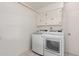 A laundry room with modern washer and dryer units, plus overhead cabinet storage at 4803 W Harmont Dr, Glendale, AZ 85302