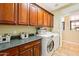 A well-organized laundry room with cherry cabinets, countertops, and a modern washer and dryer at 5136 W Trotter Trl, Phoenix, AZ 85083