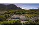 Luxury home with a pool and basketball court nestled in a green landscape with mountain views at sunset at 5615 N Invergordon Rd, Paradise Valley, AZ 85253