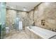 Bright main bathroom featuring travertine stone walls, a soaking tub and glass enclosed shower at 7131 E Rancho Vista Dr # 7011, Scottsdale, AZ 85251