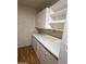 A compact kitchen features white cabinets, countertops and shelving against a wall covered with woodgrain wallpaper at 7750 E Broadway Rd # 604, Mesa, AZ 85208