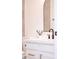 Bathroom vanity with white cabinets, gold pulls, black faucet, sleek mirror, and modern neutral wall paint at 7838 N 110 Ln, Glendale, AZ 85307