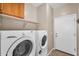 Efficient laundry room features a washer, a dryer, upper cabinets, and a convenient access door at 1081 W Stephanie Ln, San Tan Valley, AZ 85143