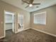 Cozy bedroom featuring carpet flooring, a ceiling fan, and a view into the walk-in closet and bathroom at 11216 W Apache St, Avondale, AZ 85323