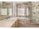 Elegant bathroom featuring double sinks, soaking tub, and walk-in shower with natural stone tile at 1245 E Emile Zola Ave, Phoenix, AZ 85022