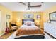 Cozy bedroom with a dark wood bed frame, ceiling fan, and bright yellow walls at 1329 E Catalina Dr, Phoenix, AZ 85014