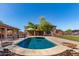Backyard pool features beautiful stone accents, fountains, basketball hoop, and shaded patio with desert landscaping at 14107 W Christy Dr, Surprise, AZ 85379