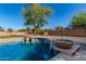 Beautiful backyard pool features stone accents and water feature, surrounded by desert landscaping and privacy fencing at 14107 W Christy Dr, Surprise, AZ 85379