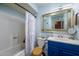 Charming bathroom with blue vanity, decorative mirror, and shower-tub combination at 15212 N 37Th Ave, Phoenix, AZ 85053