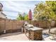 An outdoor kitchen on the patio with a grill, stone accents, and a red umbrella for shade create an inviting backyard space at 19824 N 14Th Pl, Phoenix, AZ 85024