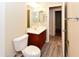 Neat bathroom showcasing wood-grain floors, a dark wood vanity, and a toilet with white tile walls at 21050 E Tierra Grande --, Queen Creek, AZ 85142