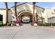 Striking entrance with palm trees, stucco arches, and manicured greenery, offering a glimpse of the community's beauty at 22504 N San Ramon Dr, Sun City West, AZ 85375