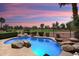 A beautiful backyard pool with rock features and a view of the golf course at sunset at 22504 N San Ramon Dr, Sun City West, AZ 85375