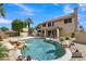 Backyard view of a sparkling pool with rock features, landscaping, and a two-story home in the background at 2340 W Myrtle Dr, Chandler, AZ 85248