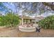 Serene backyard featuring a fire pit, mature trees, and well-maintained desert landscaping at 27158 W Potter Dr, Buckeye, AZ 85396