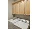 Bright laundry room with wood cabinets, washer, and dryer, perfect for efficient chore management at 27158 W Potter Dr, Buckeye, AZ 85396