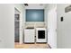 This laundry room offers a blue accent wall, white washer and dryer, and tile backsplash at 3076 E Dunbar Dr, Phoenix, AZ 85042