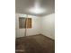 Empty bedroom requiring repairs; window is boarded and carpet shows wear at 3434 W Augusta Ave, Phoenix, AZ 85051