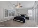 Spacious bedroom featuring plush carpet, a ceiling fan, and bright windows with white shutters at 6459 E Sugarloaf St, Mesa, AZ 85215