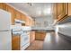 Kitchen with white appliances, wood cabinetry, and tile flooring at 813 N Gilbert Ave, Casa Grande, AZ 85122