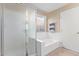 Bathroom with a glass enclosed shower, a soaking tub, a large window, and tan walls at 8606 W Caribbean Ln, Peoria, AZ 85381